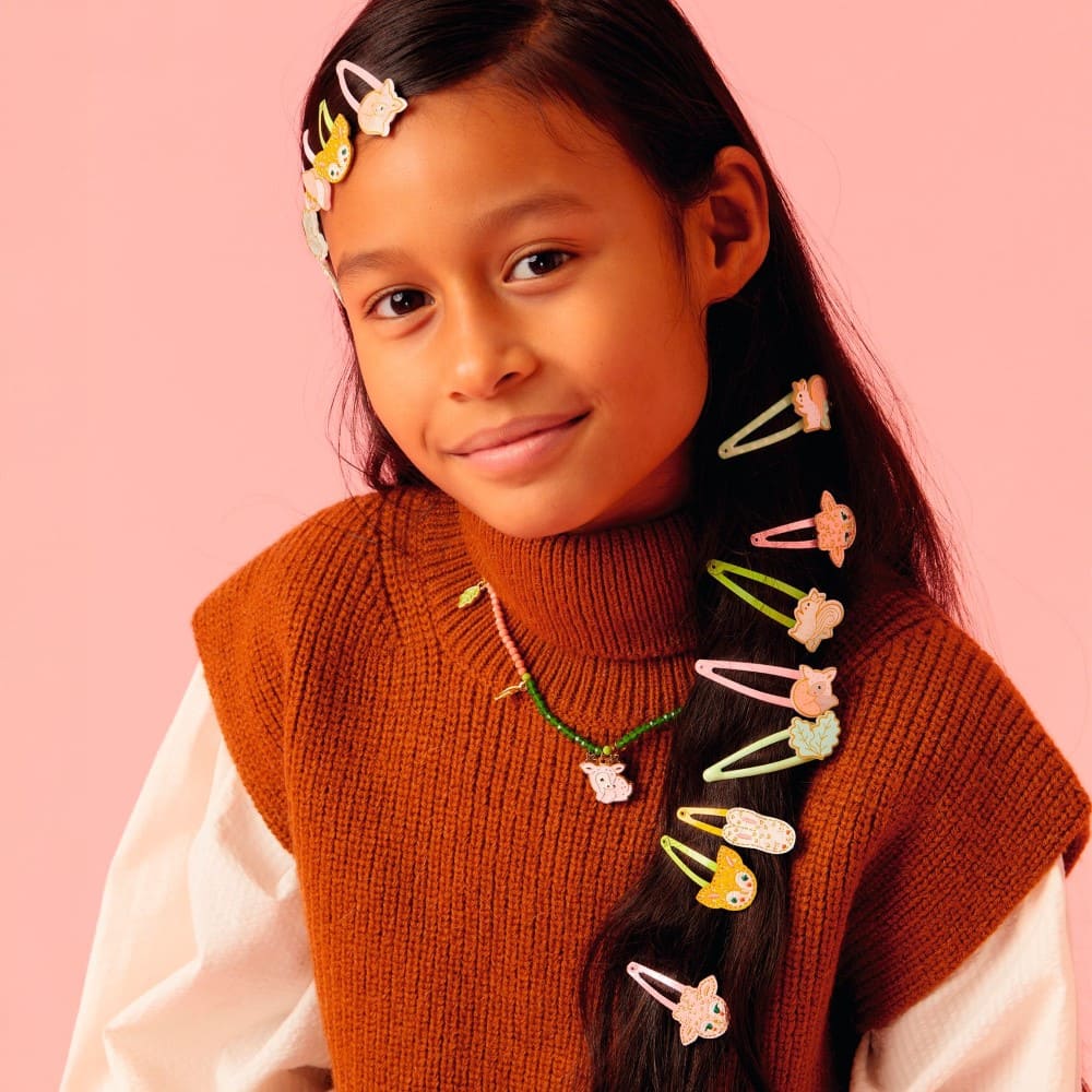 Young girl with colorful hair clips in her hair against a pink background