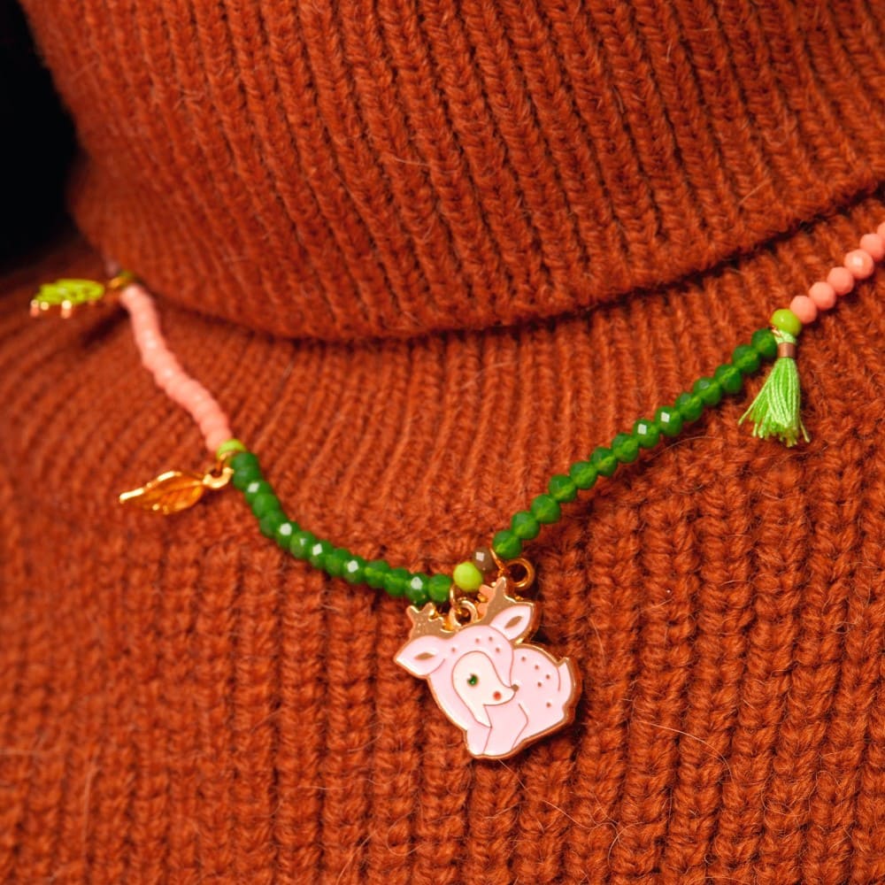 Bracelet with green beads and a pink deer charm on a brown textured background