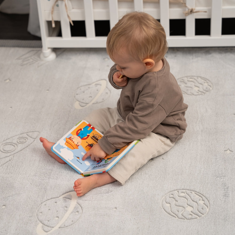 Baby sitting on a textured rug reading a book