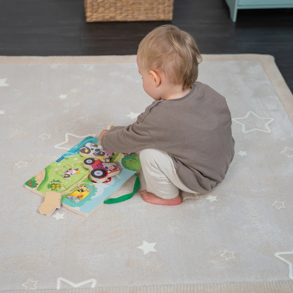 Child playing with a toy on a star-patterned mat