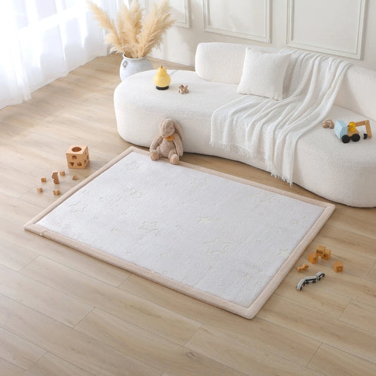 White rug on a wooden floor with toys around, in front of a white sofa.
