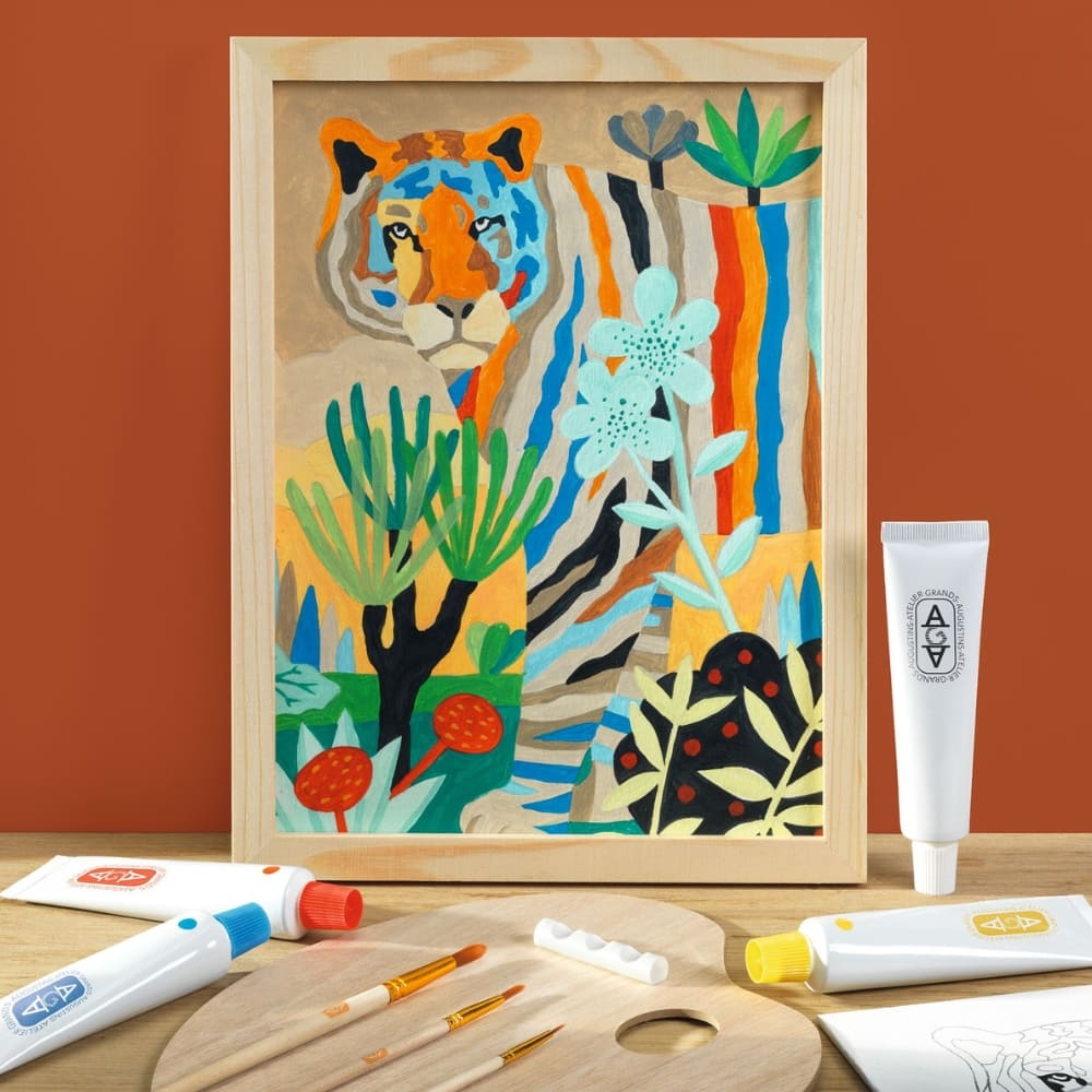 Framed colorful tiger artwork on a wooden surface with art supplies.