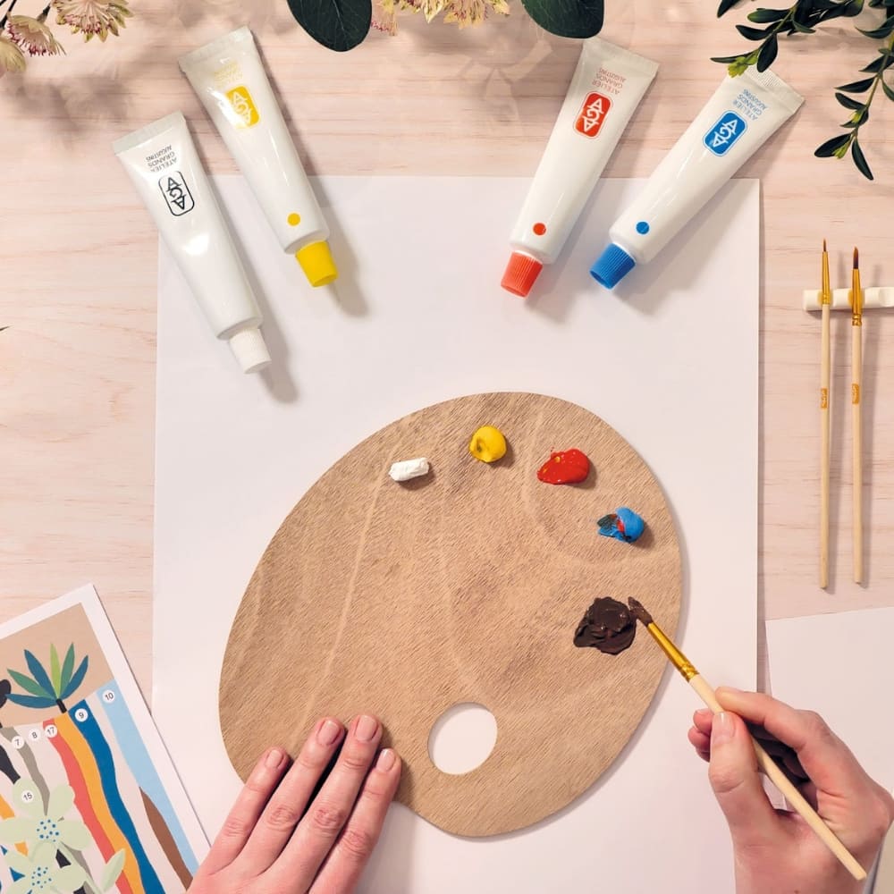 Artistic setup with paint tubes, a palette, and a brush on a light surface.