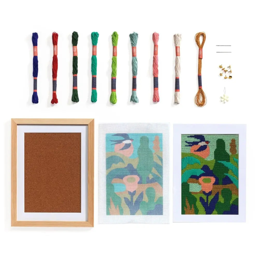 Set of cross-stitch threads and framed artworks on a white background