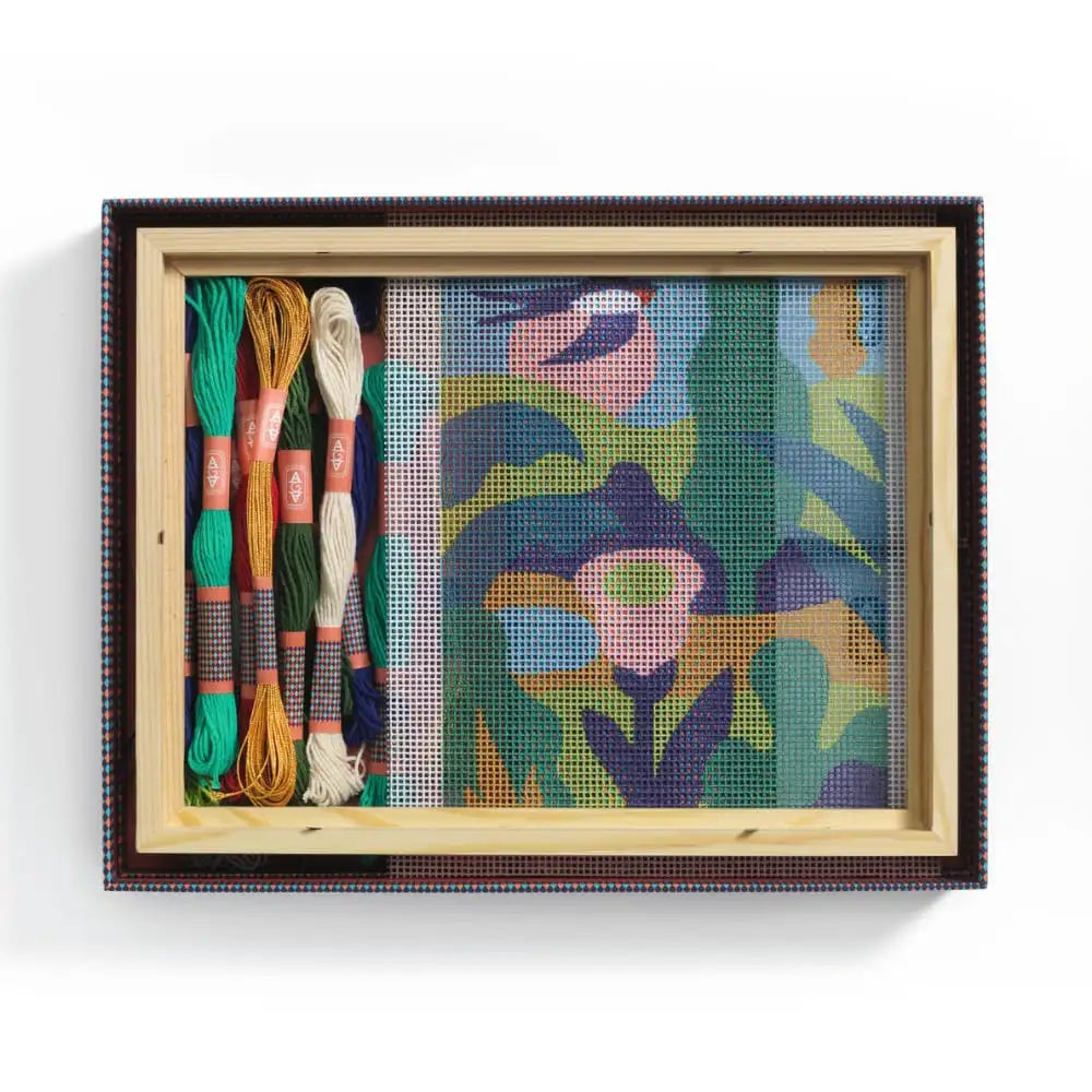 Framed needlepoint with colorful threads on a white background