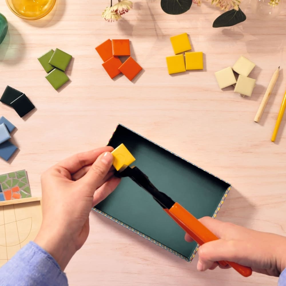 Person using a tool to manipulate colorful geometric shapes on a wooden surface