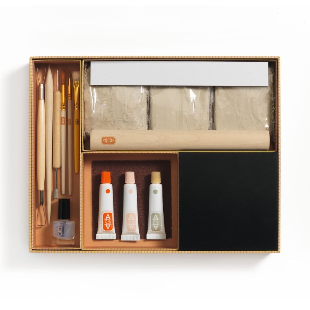 Art supply set with brushes, tubes of paint, and a black board in a box on a white background