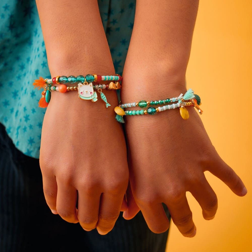 Close-up of hands wearing colorful beaded bracelets against a yellow background
