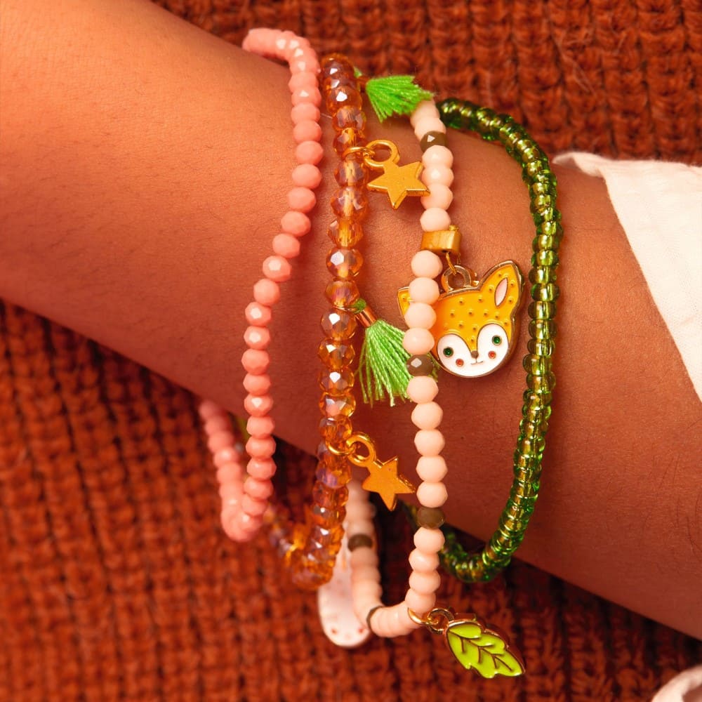 Close-up of a wrist wearing multiple colorful beaded bracelets with charms on an orange textured background.