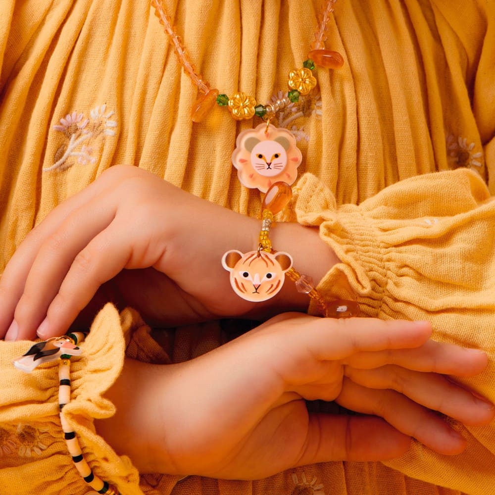 Child's hands wearing lion-themed bracelets on a yellow background