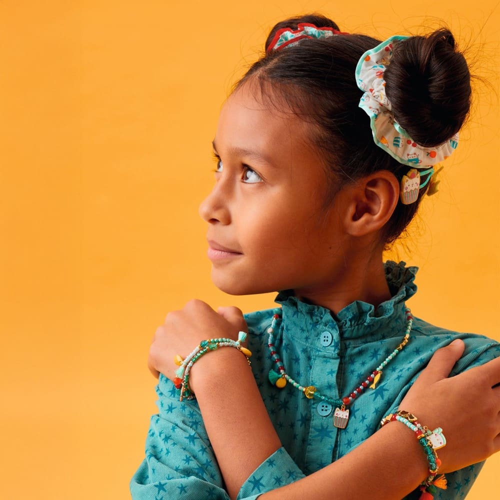 Young girl with colorful hair accessories and jewelry against a yellow background