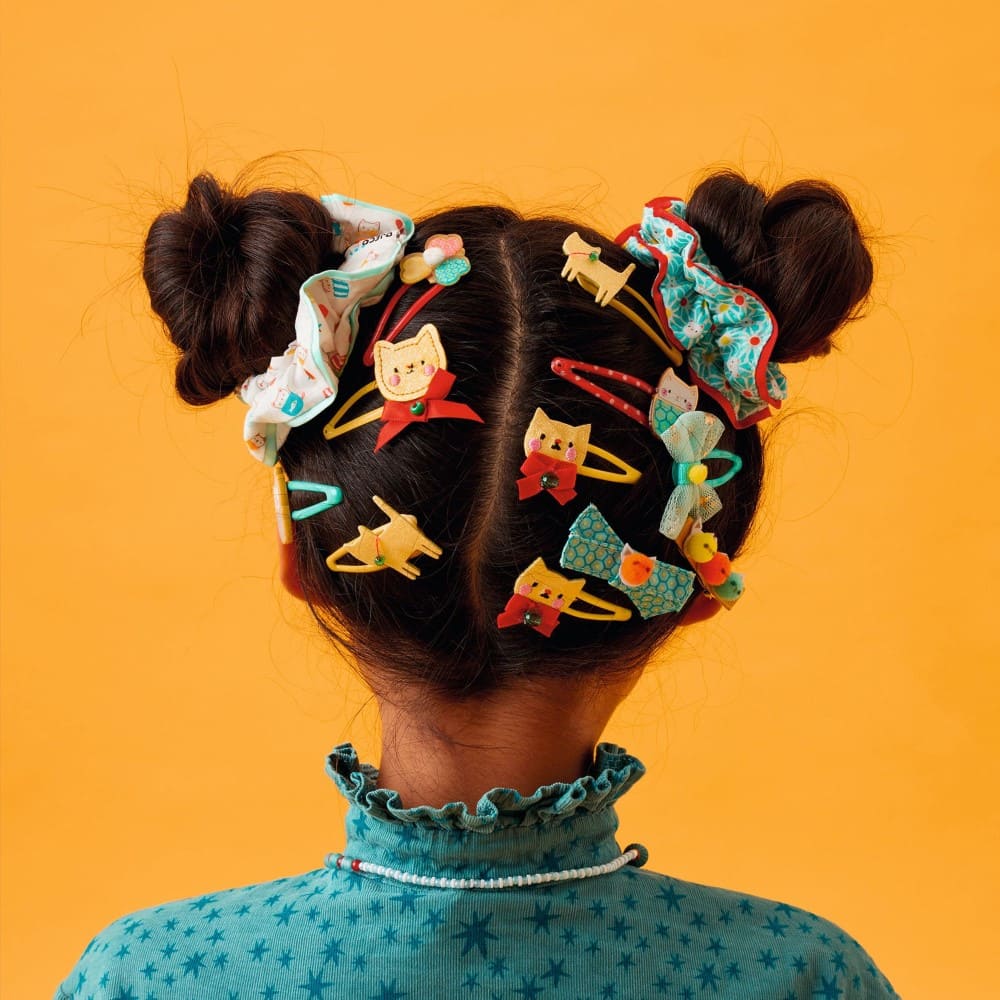 Person with colorful hair clips in their hair against an orange background