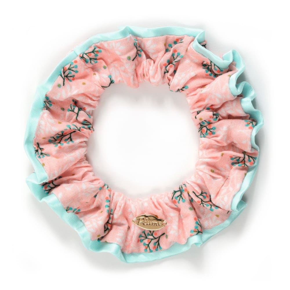 Pink floral scrunchie with a brand logo on a white background