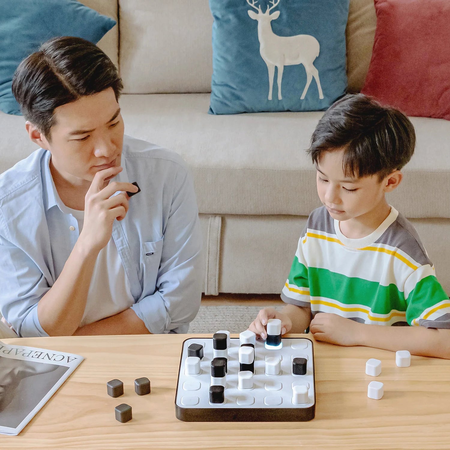 Man and child playing a board game together on a table.