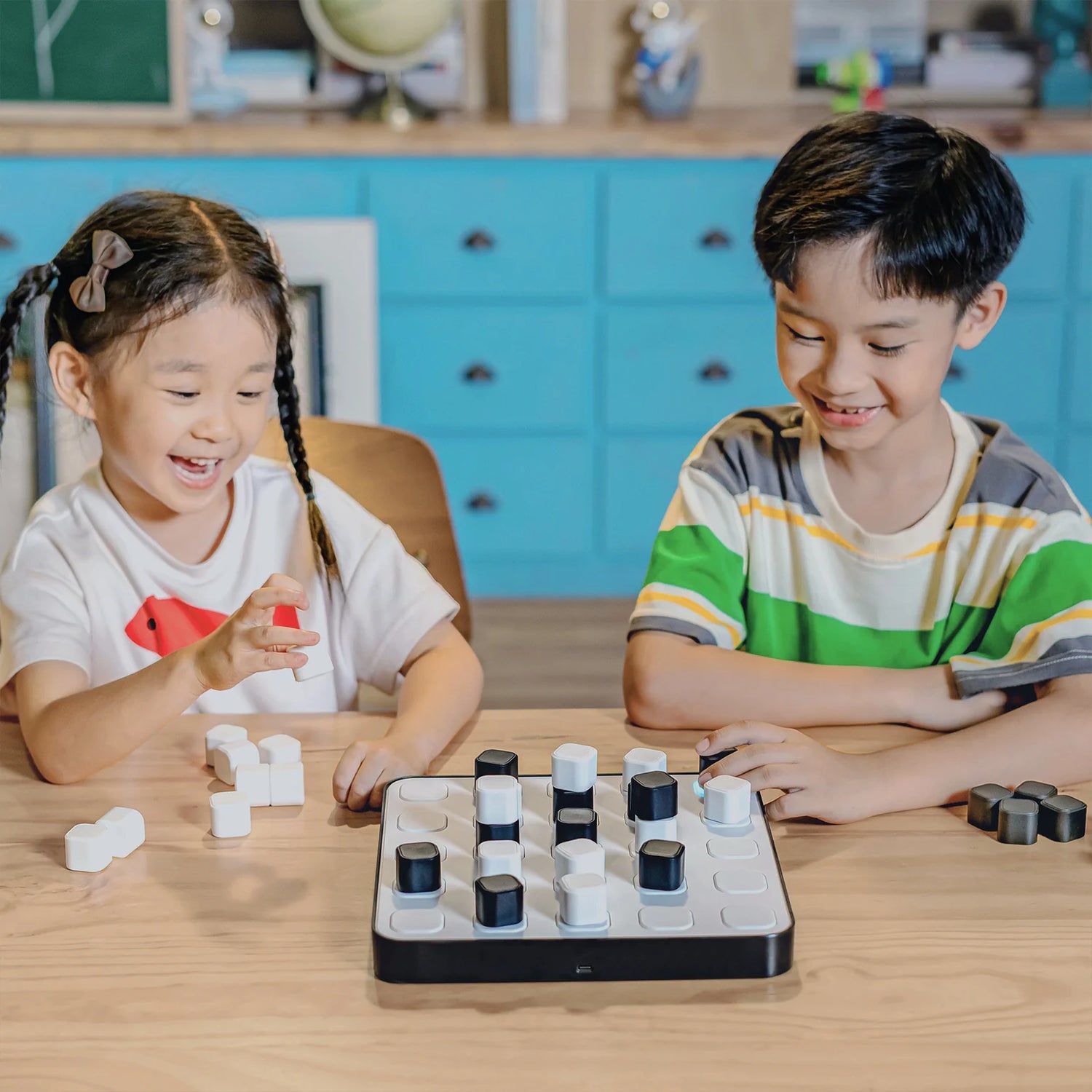 Two children playing with a board game on a wooden table.