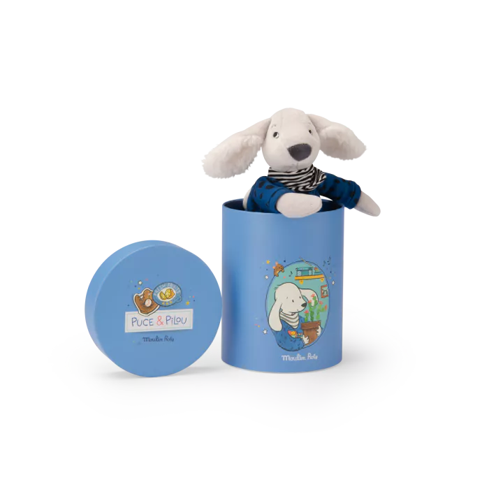 Stuffed dog toy in a blue cylindrical container with 'Puce & Pilou' branding on a white background.