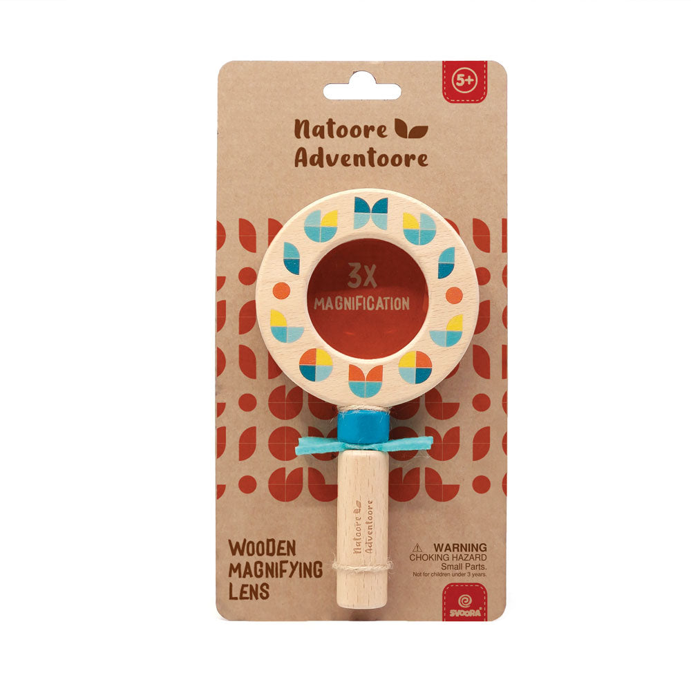 Wooden magnifying lens with colorful design on a patterned packaging by Natoore Adventoore.